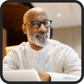 A confident, middle-aged Black man wearing glasses and a white shirt, depicting a customer review on the Prostadine official website.